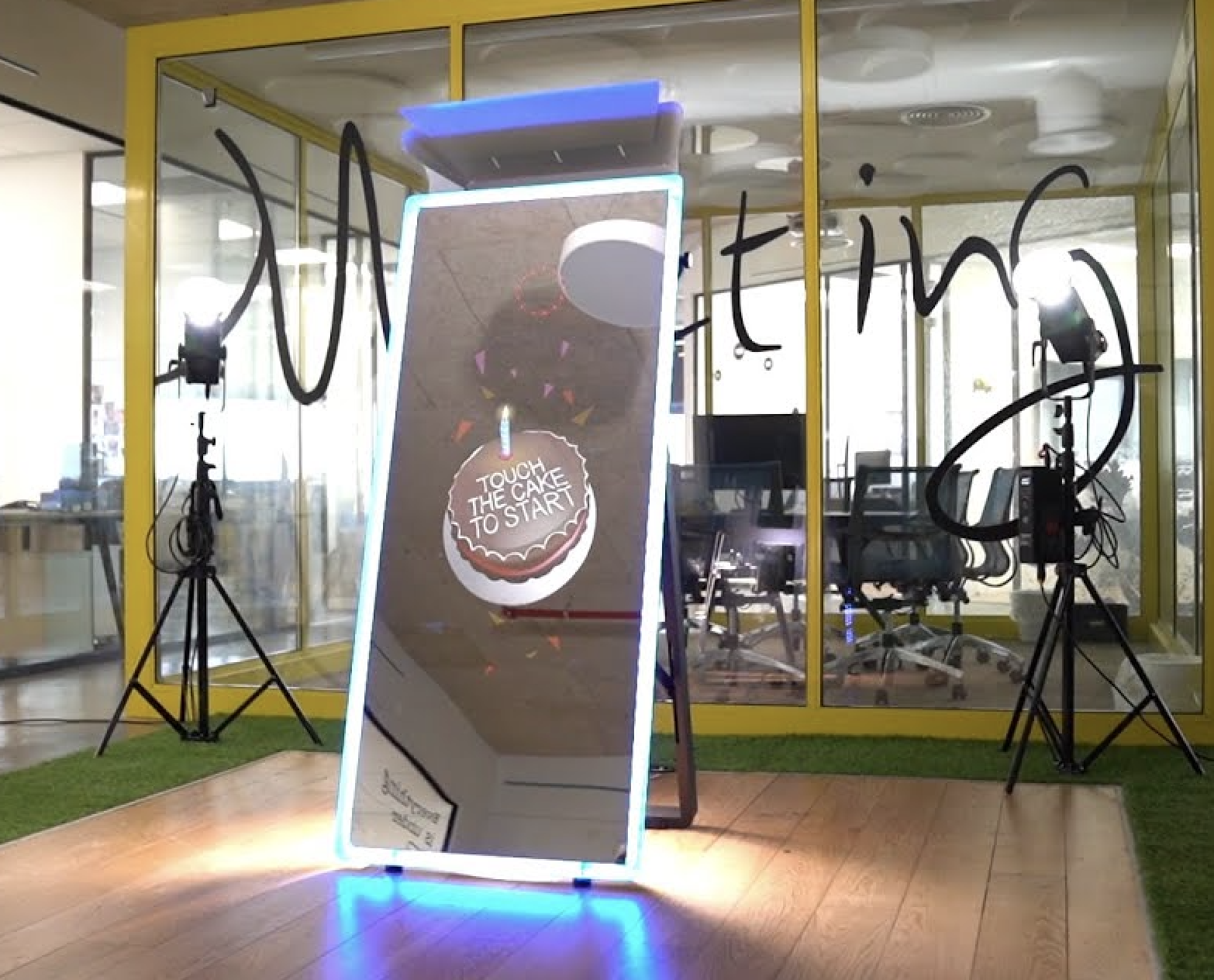 Illuminated full-length mirror booth with a glowing blue edge showing a cake touch-to-start animation